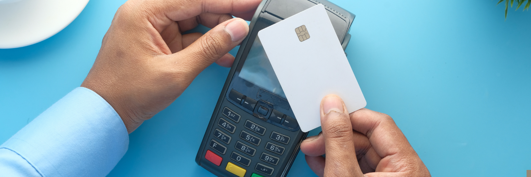 A person holds a white credit card over a payment terminal, ready to tap for a transaction. The image illustrates electronic payment processing, relevant to understanding effective rates for credit card transactions.